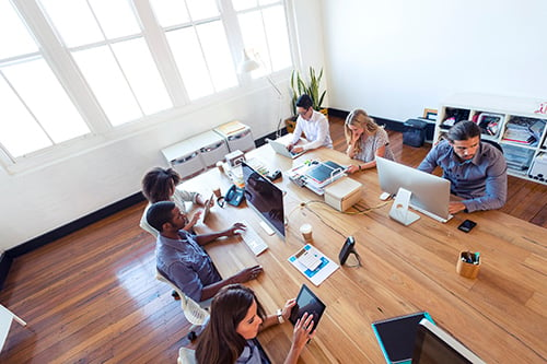 A group of people testing on various mobile devices sitting at a large table